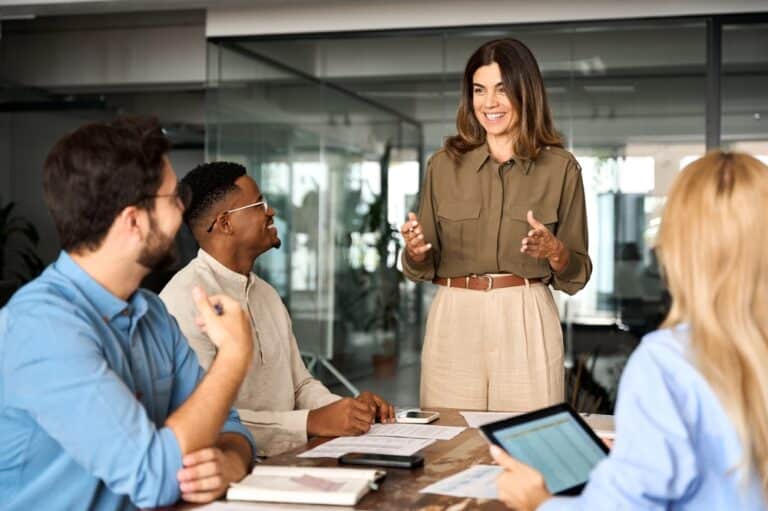 Confident businesswoman leading a strategic marketing discussion with a diverse team, representing MLCworks' Fractional CMO services.